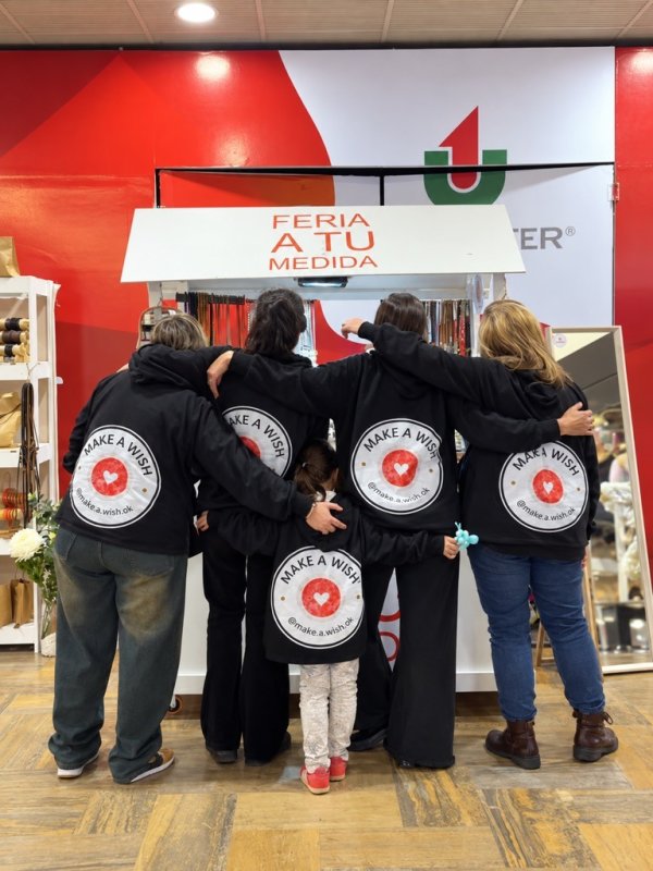 El equipo Make a Wish de espaldas, con los buzos de la marca, frente al puesto